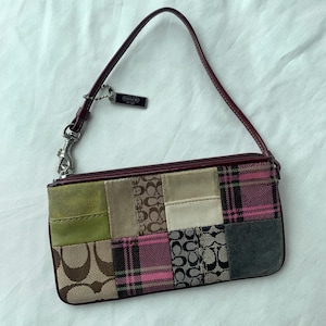 May include: A rectangular wristlet featuring a patchwork design of various textures and patterns, including pink plaid, brown and black signature logo canvas, olive green suede, and cream leather. It has a dark red strap and a Coach brand tag.