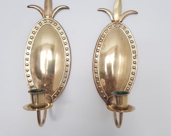 Puede incluir: Un par de apliques de pared de metal dorado con diseño de piña. Cada aplique tiene un portavelas y una placa posterior ovalada decorativa.