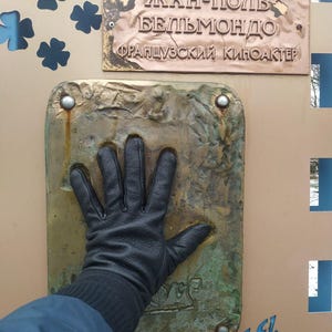 May include: A bronze plaque with the text "JEAN-PAUL BELMONDO FRAN&Ccedil;AIS CIN&Eacute; ACTEUR" and a handprint in the bronze below the plaque.