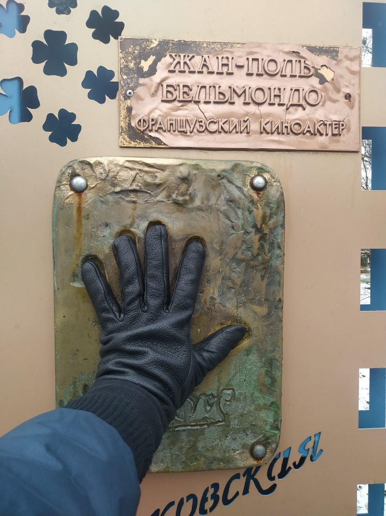 May include: A bronze plaque with the text "JEAN-PAUL BELMONDO FRAN&Ccedil;AIS CIN&Eacute; ACTEUR" and a handprint in the bronze below the plaque.