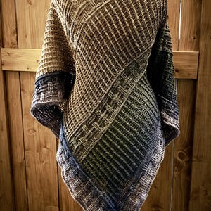 Könnte beinhalten: Ein dreieckiger Schal mit einem Waffel-Stichmuster in Braun-, Grün- und Blautönen. Der Schal ist gehäkelt und hat einen Fransenrand.