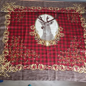 Könnte beinhalten: Ein rechteckiger rot-schwarz karierter Schal mit einem Hirschporträt in der Mitte. Der Hirsch ist in einem Oval mit goldenen Akzenten gerahmt. Der Schal hat einen braunen Rand mit goldenen Schnörkeln und Astmustern.