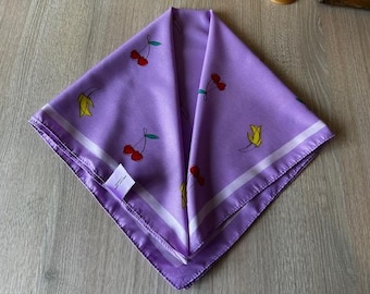 Pañuelo de seda vintage con estampado de frutas: bandana retro de satén lavanda con cerezas y plátanos. Elegante accesorio de moda vintage.