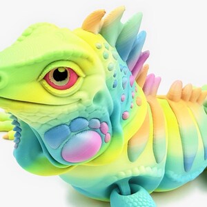 May include: A 3D printed articulated iguana figurine featuring a vibrant rainbow gradient color scheme. The lizard has a textured surface with prominent scales, a spiky crest along its back, and large eyes with pink and black details.
