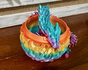 May include: A rainbow colored dragon planter with a textured, scaly design. The planter is made of ceramic and has a wide, open mouth.