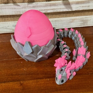 May include: A pink dragon egg with a gray, spiky nest and a matching pink and gray dragon tail.