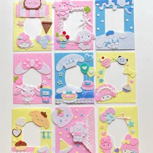 Pode incluir: Nove molduras de feltro coloridas com vários desenhos de personagens de desenhos animados. Cada moldura tem uma abertura central e é decorada com recortes de feltro de animais, comida e outros elementos fofos. As molduras são em tons de rosa, azul e amarelo.