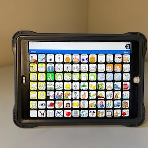 May include: A black tablet computer with a touch screen displaying a grid of colorful icons. The icons are arranged in rows and columns and include images of people, animals, objects, and actions. The text "Menu" is visible at the top of the screen.