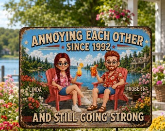 May include: A rectangular metal sign featuring a cartoon illustration of two people sitting in red chairs by a lake, holding drinks. The text reads: ANNOYING EACH OTHER SINCE 1992, LINDA, ROBERT, AND STILL GOING STRONG. The sign has a weathered border.