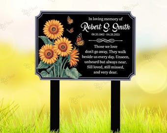 May include: A black memorial garden stake with a decorative border. The sign features sunflowers and butterflies, with the text "In loving memory of Robert S. Smith" and dates. The bottom has two black stakes.