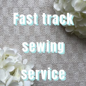 Può includere: Un tessuto beige chiaro con un sottile motivo a spina di pesce, accentuato da fiori di ortensia bianchi negli angoli. Il testo "Fast track sewing service" è sovrapposto in bianco con un'ombra azzurra, centrato sul materiale strutturato.