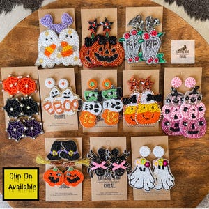 May include: A collection of beaded Halloween-themed earrings, including ghosts, pumpkins, bats, and witch hats. The earrings are in various colors, such as orange, black, purple, and white, and are displayed on brown cards.