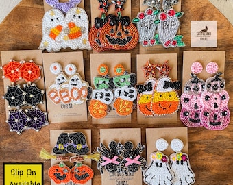 May include: A collection of beaded Halloween-themed earrings, including ghosts, pumpkins, bats, and witch hats. The earrings are in various colors, such as orange, black, purple, and white, and are displayed on brown cards.