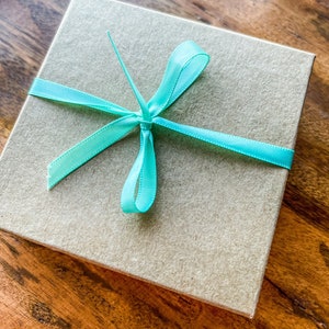May include: A brown gift box with a light blue ribbon tied in a bow.