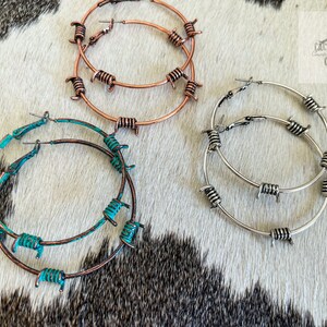 May include: Three pairs of hoop earrings with barbed wire accents. The earrings are in silver, copper, and turquoise.