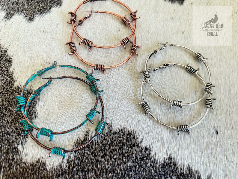 May include: Three pairs of hoop earrings with barbed wire accents. The earrings are in silver, copper, and turquoise.