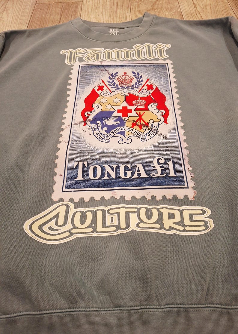 May include: Grey sweatshirt with a large Tonga stamp graphic. The stamp design includes a coat of arms and the text "TONGA &pound;1". The word "Culture" is written in a stylized font below the stamp.