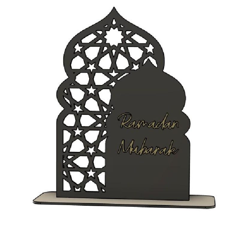 May include: A black laser-cut wooden Ramadan Mubarak decoration. The design features an arched silhouette with a geometric star pattern and the words "Ramadan Mubarak" in a decorative font.