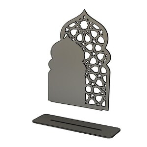 May include: A grey, laser-cut decorative piece with an arched top and geometric star patterns. The design includes a rectangular base with a slot, and the main structure has a solid section and an openwork design. The overall shape resembles a mosque.