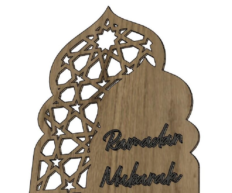 May include: Wooden Ramadan Mubarak decoration with a decorative cutout design. The top portion features a geometric pattern with star shapes. The words "Ramadan Mubarak" are written in a script font.