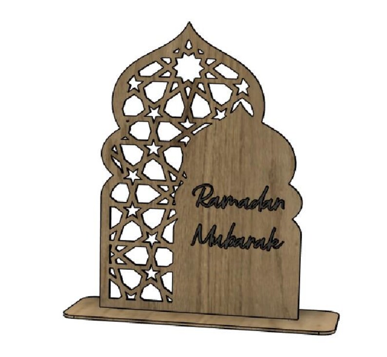 May include: Wooden Ramadan Mubarak decoration. The design features an arched shape with intricate star cutouts and the words "Ramadan Mubarak" in a script font. The base is rectangular, providing stability for the decorative piece.