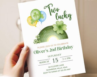 May include: A white invitation card with the text "Two lucky" in green script. The card features watercolor illustrations of balloons, a rainbow, and shamrocks. The invitation is for Oliver's 2nd birthday, March 15th.