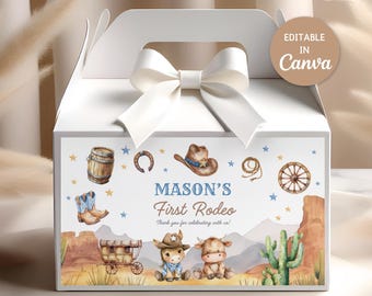 Puede incluir: Caja de regalo blanca con un lazo blanco y un panel frontal decorativo. El panel presenta un tema "First Rodeo de Mason" con ilustraciones de un sombrero de vaquero, botas y un vagón. La caja mide 15,88 x 8,89 cm.