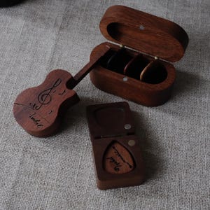 以下が含まれることがあります： 木製の箱3個セット。1つはギター型で音符と「Isabel」の名前入り。もう1つは楕円形で開いており、3つの円形コンパートメントがあります。3つ目は、ギターピックが入った小さな正方形の箱で、こちらも彫刻が施されています。