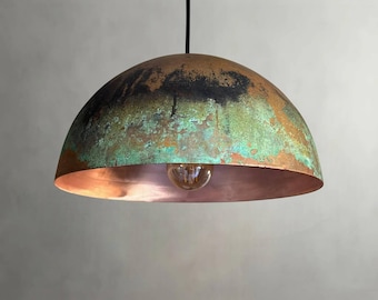 May include: A dome-shaped pendant light fixture with a copper interior and a weathered exterior finish. The exterior features a mix of brown, black, and green hues, creating a rustic appearance. A single light bulb is visible inside the fixture.