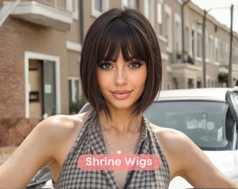 May include: A woman with a short, dark brown bob wig and fringe. She is wearing a plaid halter top and a necklace. The text "Shrine Wigs" is displayed on a pink banner.