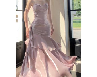May include: A light pink, floor-length, strapless dress with a ruffled skirt and a fitted bodice.