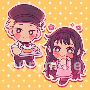 Peut inclure: Deux autocollants de dessins animés sur fond jaune avec des losanges blancs. L'un représente une personne en uniforme de boulanger tenant un plateau avec un cupcake. L'autre montre une personne en robe rose tenant un cupcake.