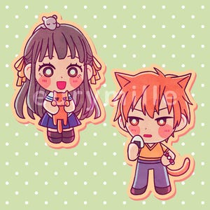 May include: Two chibi-style character stickers featuring a girl with long dark hair holding an orange cat and a boy with orange hair, cat ears, and a tail holding a rice ball. Both figures have large eyes and are rendered in a flat, colorful illustration.