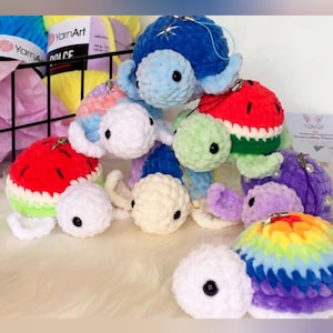 Peut inclure: Une collection de petites tortues en crochet faites à la main dans diverses couleurs, incluant un motif pastèque rouge et vert, une carapace arc-en-ciel, des modèles unis bleus, violets et blancs, avec des yeux en plastique noir et une boucle.