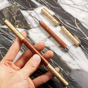 May include: Two wooden tools with gold accents and engraved sayings. The first tool has the saying "Wake up & smell the coffee" and the second tool has the saying "Coffee: Because adulting is hard."