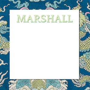 May include: A white notepad with the name "MARSHALL" in light green letters. The notepad is surrounded by a blue fabric with a dragon pattern in shades of green, blue, and pink.