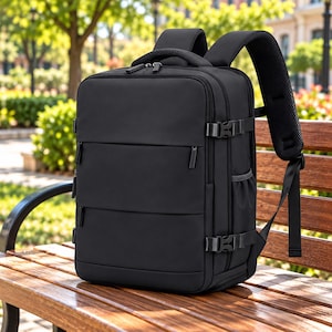 May include: A black rectangular backpack featuring multiple horizontal zipped compartments, side compression straps with plastic buckles, a top handle, and padded shoulder straps with a mesh lining for comfort and support.