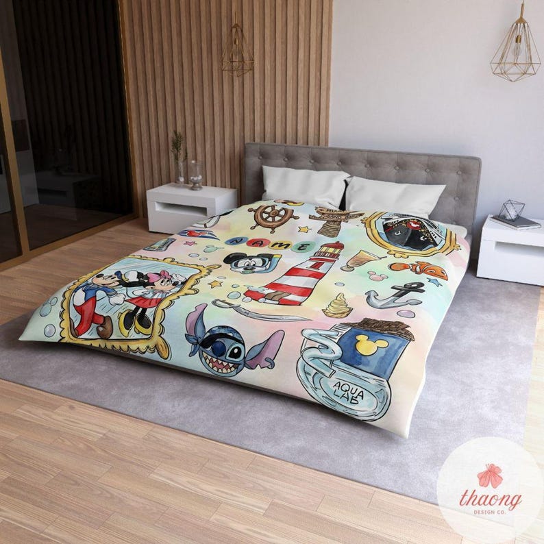 Puede incluir: Una colorida colcha con personajes de dibujos animados y elementos n&aacute;uticos. El dise&ntilde;o incluye Mickey y Minnie Mouse, Stitch, un faro, anclas y un tim&oacute;n. El fondo tiene un efecto acuarela con colores pastel.