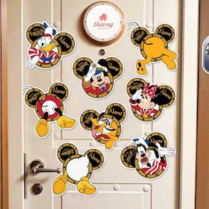 May include: Eight colorful Disney character door hangers with Mickey Mouse ears. Each hanger features a different character, including Mickey Mouse, Donald Duck, Goofy, and Pluto. The hangers are decorated with the words "Disney", "Fantasy", "Wish", "Dream", "Wonder", "Magic", and "Name".