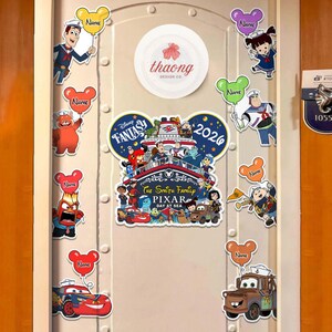 May include: A door decorated with Disney Pixar themed magnets. The magnets feature characters from various Pixar movies, including Lightning McQueen and Mater from Cars, and characters from Inside Out. The door also has a sign that says "Disney Fantasy Pixar Day at Sea 2026."
