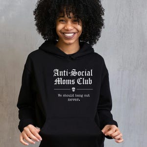 May include: Black hooded sweatshirt with the text "Anti-Social Moms Club" in a gothic font, with a skull graphic and the phrase "We should hang out never."
