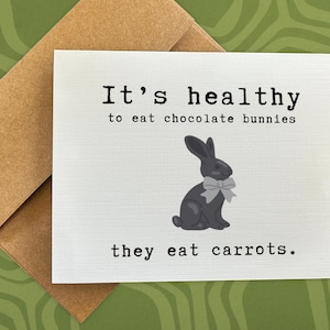 May include: A white card with the text "It's healthy to eat chocolate bunnies they eat carrots." and a black and white illustration of a chocolate bunny with a gray bow.