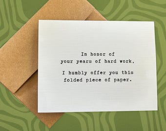 May include: A white card with the text "In honor of your years of hard work, I humbly offer you this folded piece of paper."