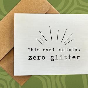 May include: A white card with black text that reads "This card contains zero glitter". The card has a simple black starburst design at the top.