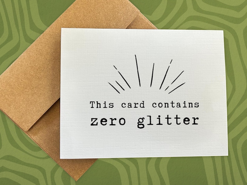 May include: A white card with black text that reads "This card contains zero glitter". The card has a simple black starburst design at the top.