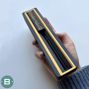 May include: A black box with gold trim and the text "Burdent Makes" on the side. The box is open and has a black interior.