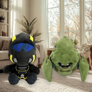 May include: Two plush toys: a black and yellow helmeted figure and a green, insect-like creature. The helmeted figure has a blue visor and skull details. The green creature has large claws and a menacing expression. Both are soft and cuddly.