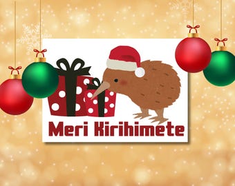 Op de afbeelding: Een feestelijke illustratie met een bruine kiwi-vogel met een kerstmuts, naast ingepakte cadeaus. Rode en groene kerstballen hangen van bovenaf. De tekst "Meri Kirihimete" staat hieronder.