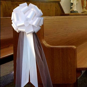 Large white bow with tulle tails displayed on a Church Pew.