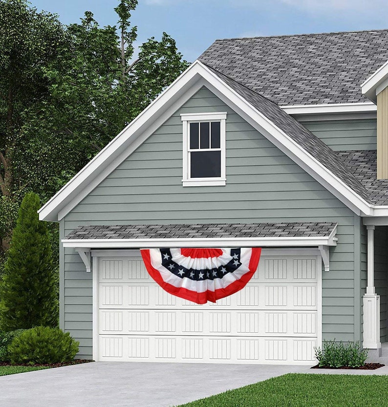 A patriotic bunting flag hanging from the garage of a lovely home.
